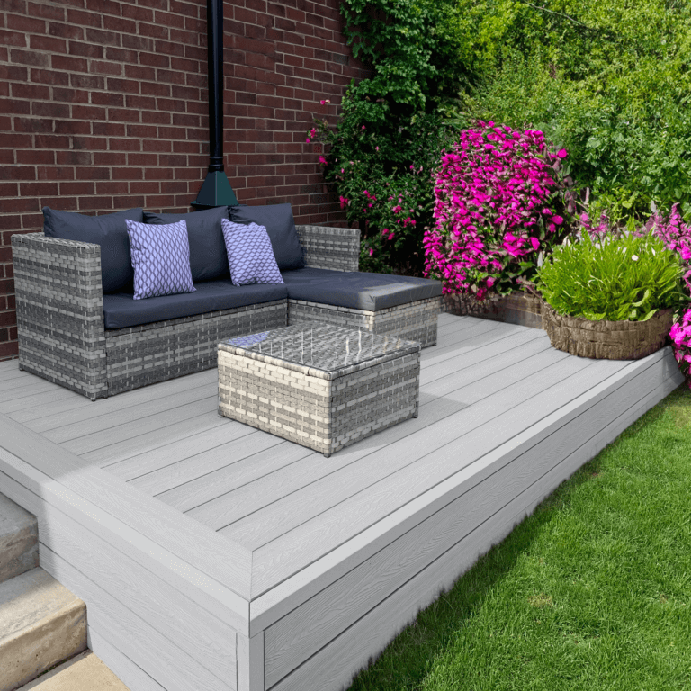 Light grey composite deck with garden sofa and flowering plants