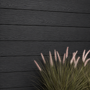 Close-up of charcoal composite cladding beside ornamental grass
