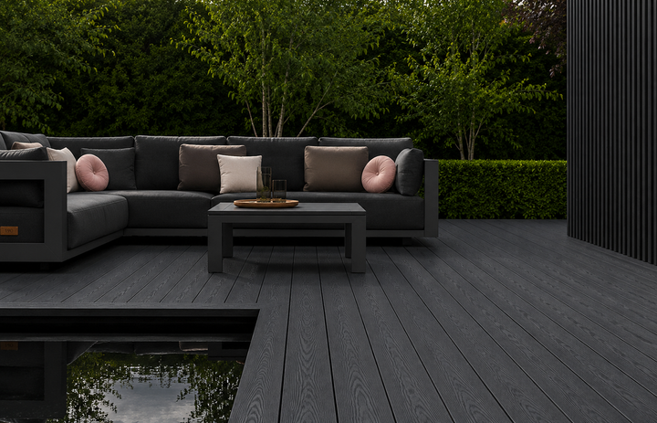 Charcoal composite decking beside outdoor sofas and a reflecting pond