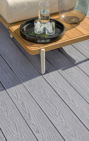 Close-up of light grey composite decking beneath a side table