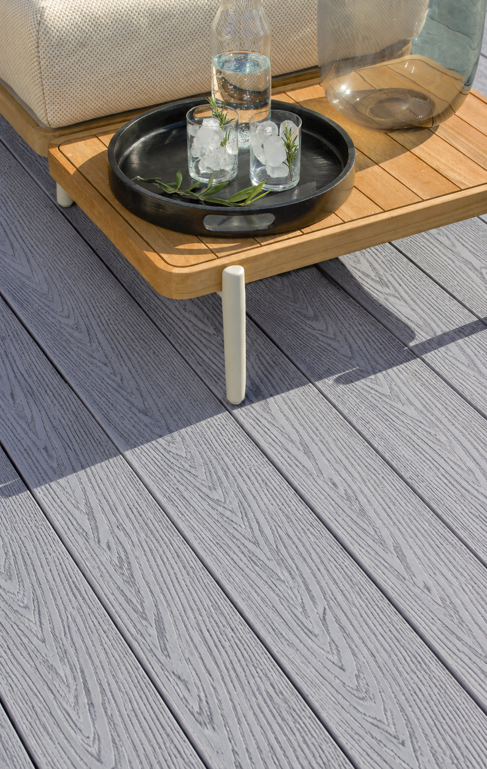 Close-up of light grey composite decking beneath a side table