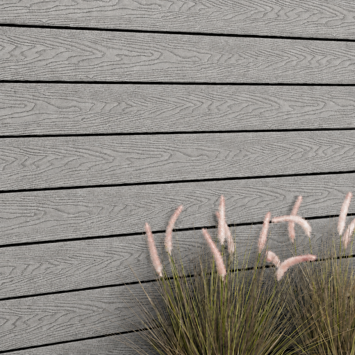 Close-up of light grey composite cladding beside ornamental grass