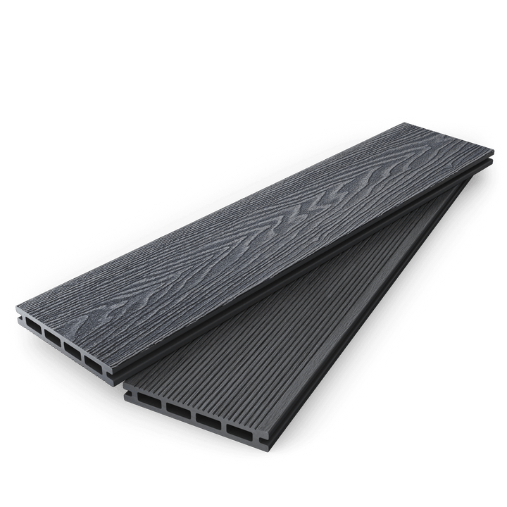 Stacked dark grey composite decking boards showing woodgrain and grooved faces