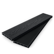 Stacked charcoal composite decking boards showing woodgrain and grooved faces